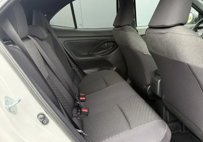Vue intérieure côté gauche des sièges arrière noirs du Toyota Yaris Cross blanc Lunaire 2026, avec portières fermées.