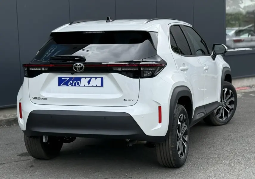 Vue 3/4 arrière droite d'une Toyota Yaris Cross 1.5 Hybrid blanc lunaire avec feux arrière full LED et vitres surteintées.