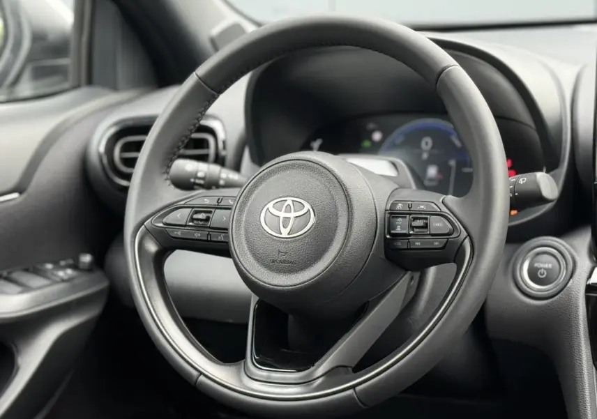 Vue rapprochée du volant cuir noir de la Toyota Yaris Cross 1.5 Hybrid 116 Design avec commandes intégrées.