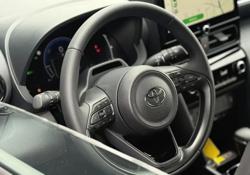 Gros plan sur le volant cuir noir de la Toyota Yaris Cross 2026 avec tableau de bord et écran tactile en arrière-plan.