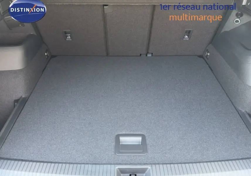 Vue du coffre spacieux et plat du Volkswagen Tiguan gris dauphin métal, montrant le revêtement intérieur uniforme et les fixations arrière.