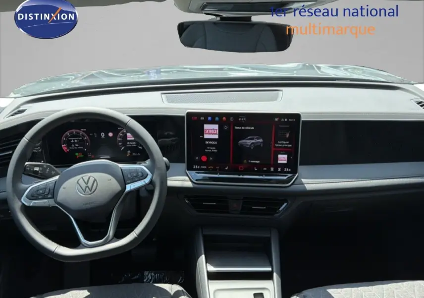 Vue frontale intérieure du Volkswagen Tiguan gris dauphin, tableau de bord moderne avec écran tactile central et volant multifonction.