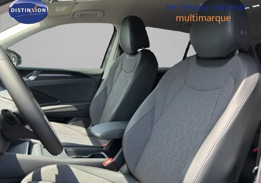 Vue intérieure du Volkswagen Tiguan 2026, sièges avant en tissu gris et cuir noir avec détails modernes.