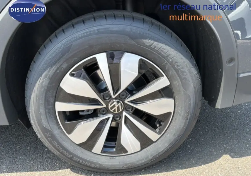 Gros plan sur la roue avant droite du Volkswagen Tiguan gris dauphin métal avec jante alliage bicolore moderne.