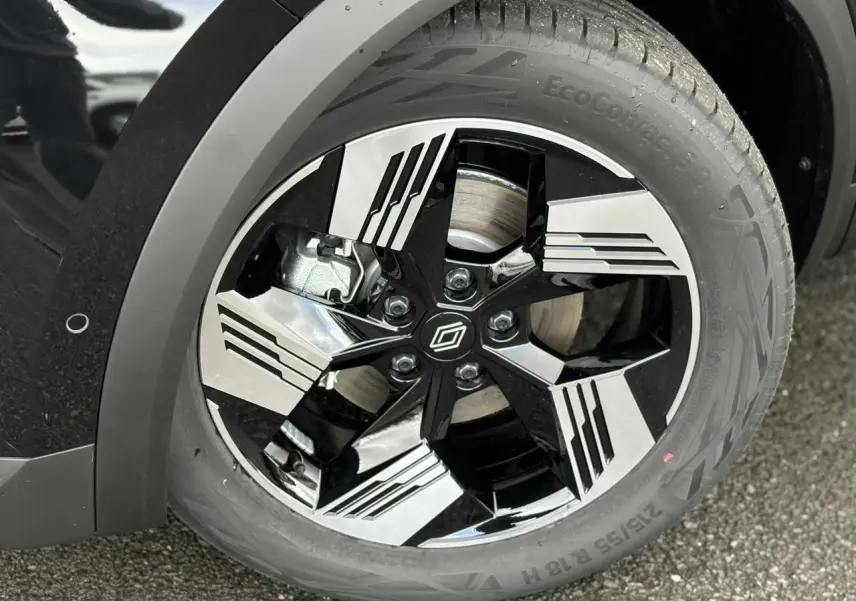 Gros plan sur la jante 18 pouces bicolore noire et argent du Renault Symbioz noir étoile, avec logo central distinctif.