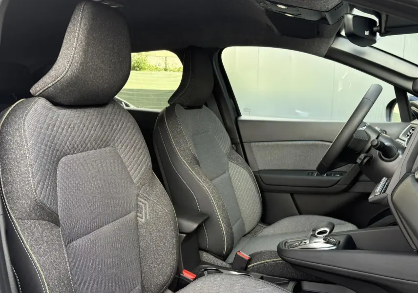 Vue intérieure côté droit du Renault SYMBIOZ 2025, sièges tissu gris avec console centrale et volant multifonction.