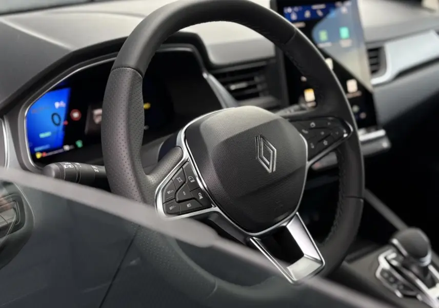 Gros plan sur le volant en cuir noir et le tableau de bord numérique du Renault Symbioz E-Tech 2025.