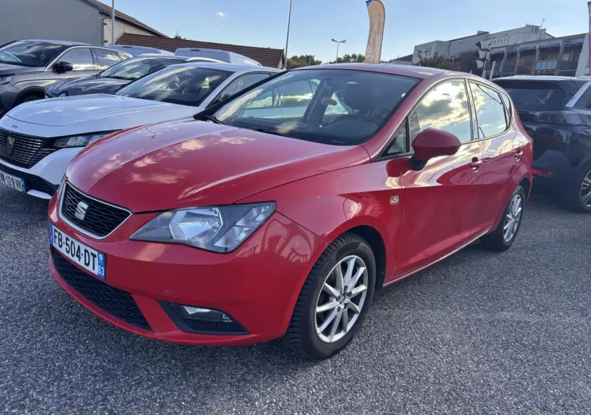 SEAT Ibiza 1.2 TSI rouge clair vue 3/4 avant droit sur parking avec jantes alliage et calandre noire.