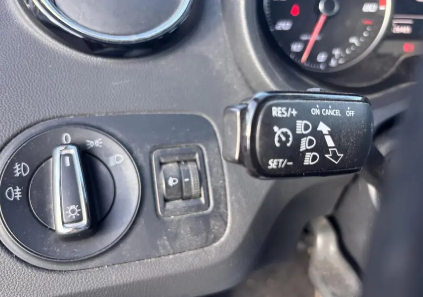 Gros plan sur les commandes d'éclairage et régulateur de vitesse du tableau de bord d'une SEAT Ibiza 2016 rouge clair.