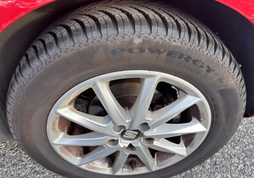 Gros plan sur la roue avant gauche d'une SEAT Ibiza rouge clair de 2016, mettant en valeur la jante alliage et le pneu Powergy.