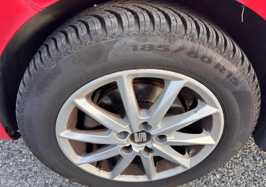 Gros plan sur la roue avant droite d'une SEAT Ibiza rouge clair de 2016 avec jante alliage à 10 branches.