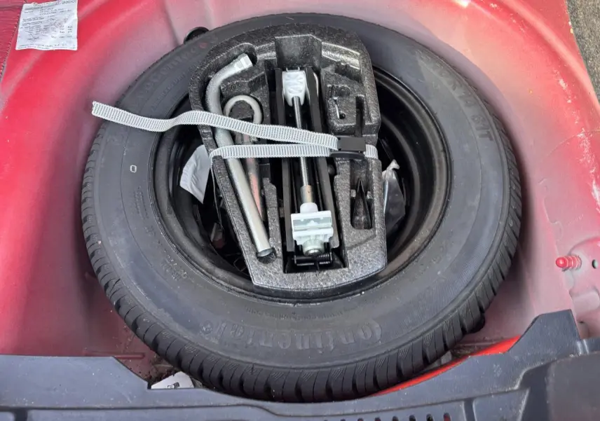 Roue de secours et outils de bord dans le coffre rouge clair d'une SEAT Ibiza 1.2 TSI Style 2016.