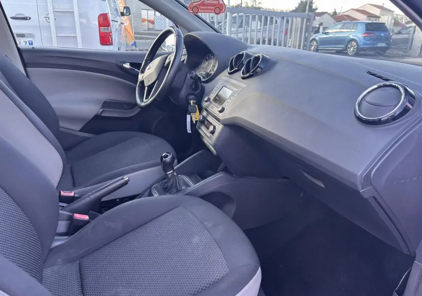 Intérieur de la SEAT Ibiza 1.2 TSI Style 2016, vue côté conducteur montrant tableau de bord et sièges noirs.