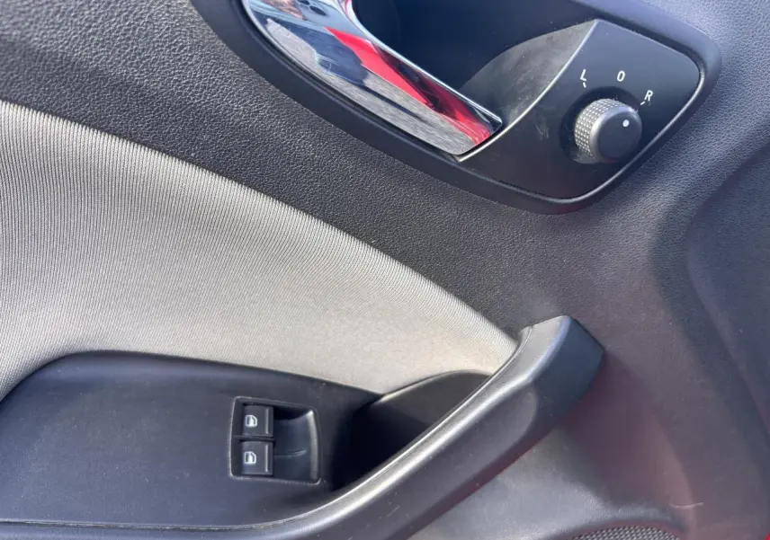 Détail de la porte côté conducteur d'une SEAT Ibiza 2016 rouge clair, avec commandes des vitres et réglage des rétroviseurs.