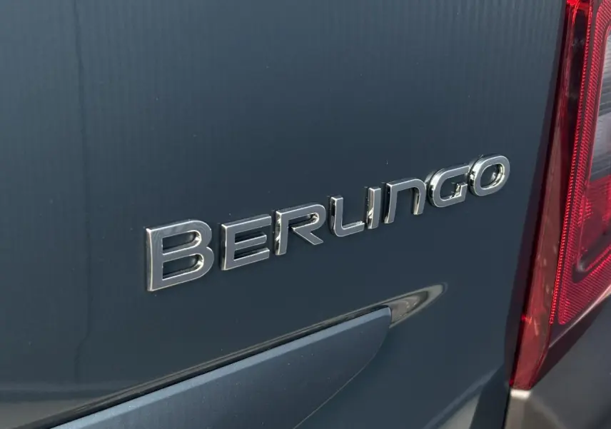Gros plan sur l'arrière bleu métallisé du Citroën Berlingo 2025 avec logo et feu arrière rouge visible.