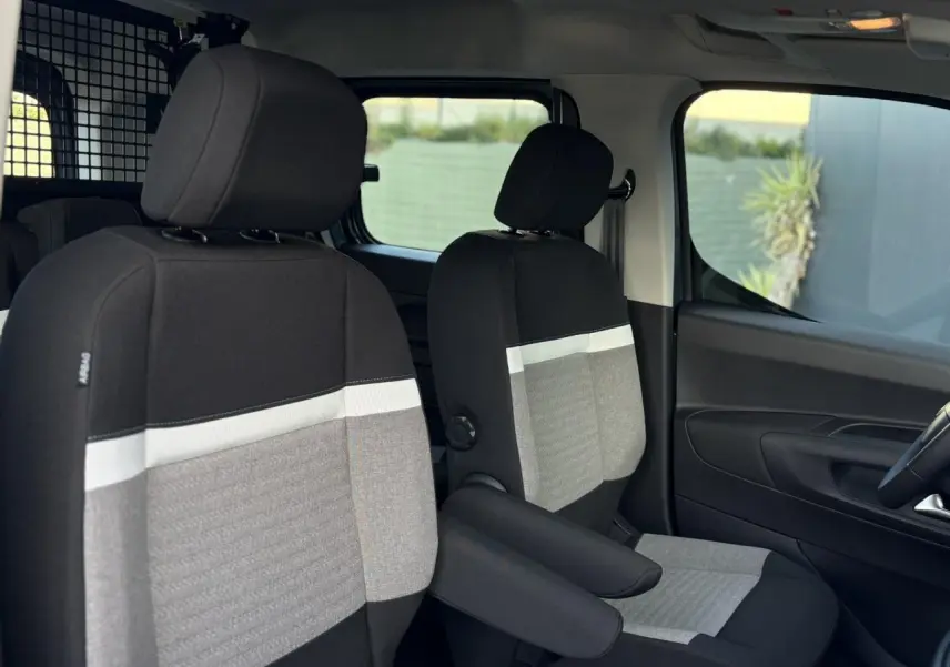 Intérieur avant du Citroën Berlingo Multispace bleu 2025, sièges tissu bicolore avec accoudoirs et séparation métallique.