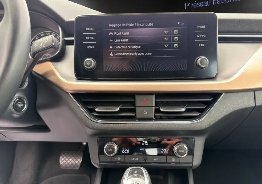 Vue intérieure côté passager du Skoda Kamiq 2023, écran tactile affichant la caméra de recul et détails bois clair.
