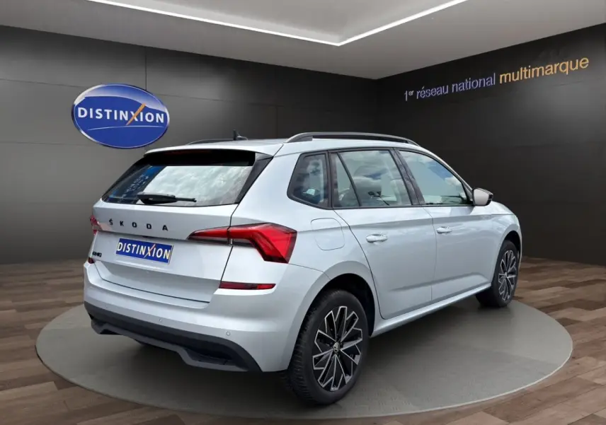Vue arrière d'un Skoda Kamiq gris clair 2023 avec feux LED et logo distinctif sur fond showroom.