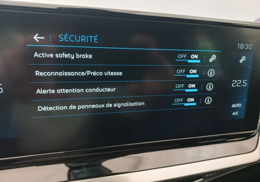 Écran tactile intérieur du tableau de bord de la Peugeot 208 PureTech 100 noir, affichant les options de sécurité activées.