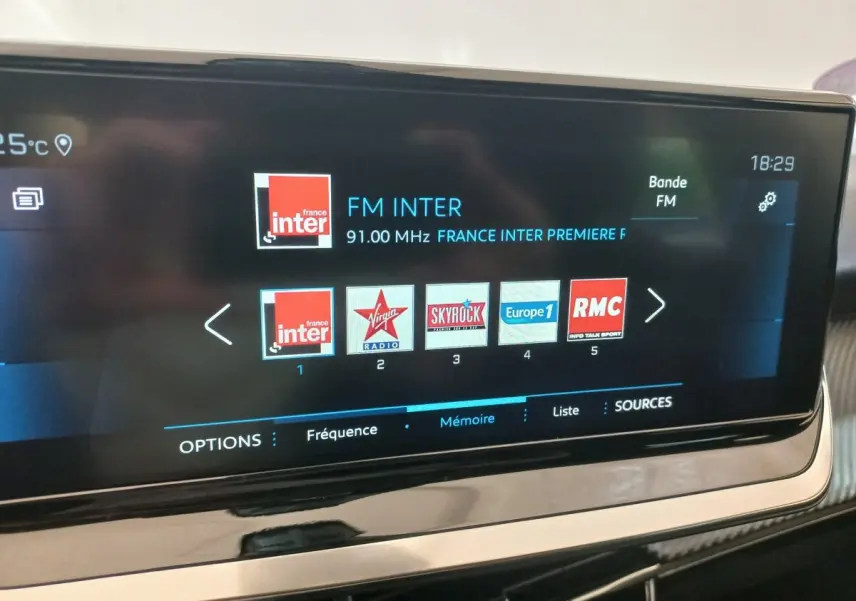 Écran tactile central de la Peugeot 208 PureTech 100 noir, affichant les stations radio FM en intérieur.