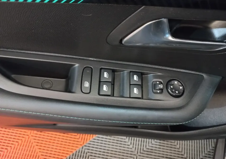 Gros plan sur la commande des vitres et rétroviseurs côté gauche de la porte intérieure noire d’une Peugeot 208 2022.
