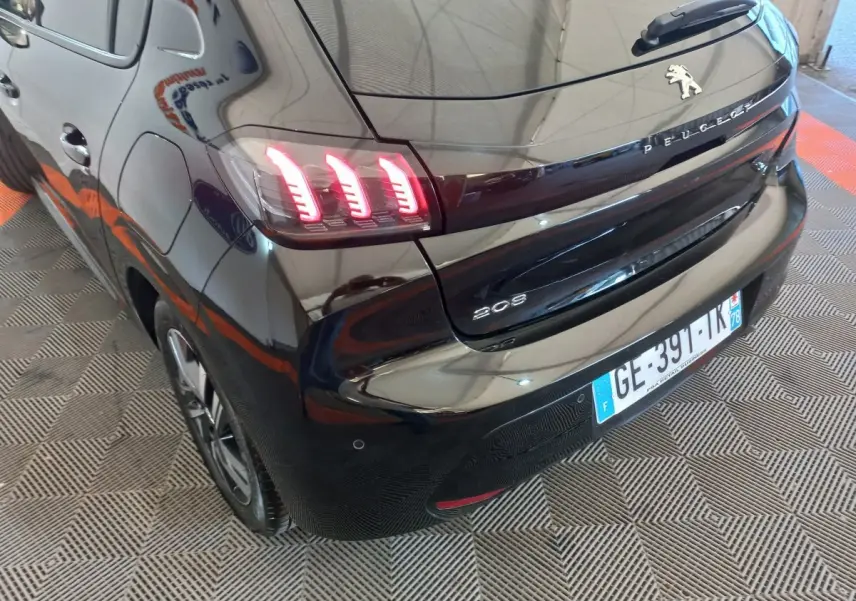 Vue 3/4 arrière gauche d'une Peugeot 208 noire de 2022 avec feux arrière LED caractéristiques allumés.