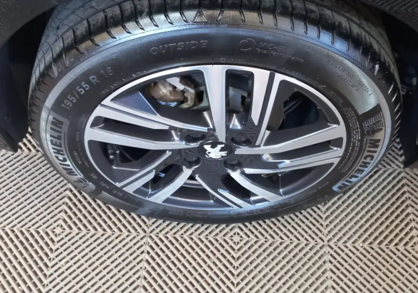 Gros plan sur la jante alliage noire et argentée de la Peugeot 208 PureTech 100, avec pneu Michelin visible.