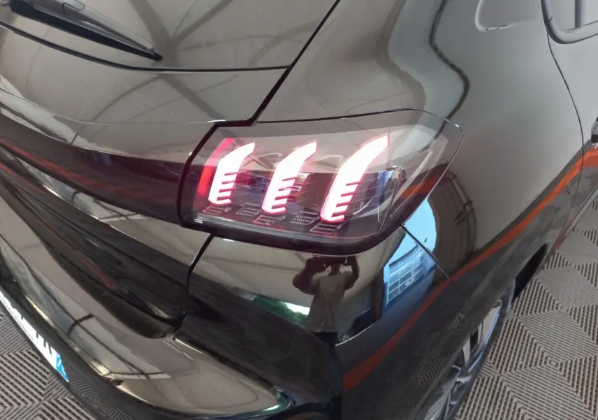 Feu arrière droit allumé d'une Peugeot 208 noire vue en gros plan sur l'arrière du véhicule.