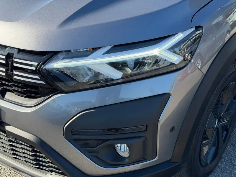 Gros plan sur l'avant droit du Dacia Jogger gris schiste métallisé, mettant en valeur le phare LED et la calandre noire.