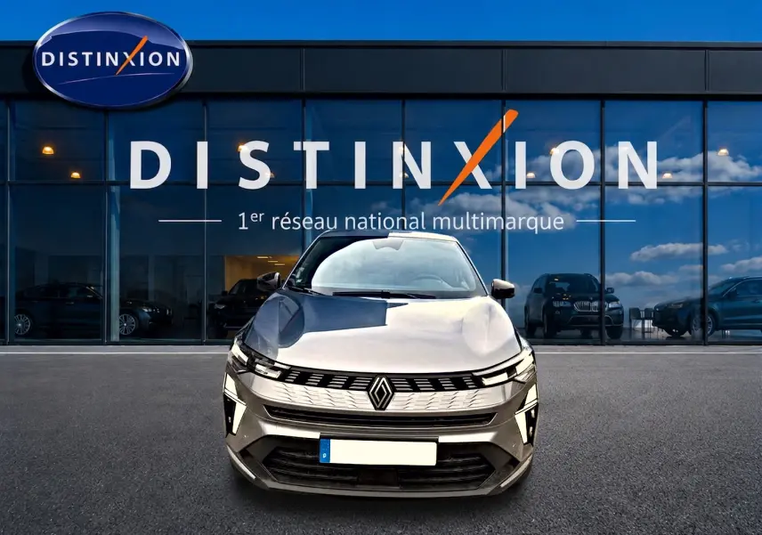Vue frontale d'une Renault SYMBIOZ gris cassiopé avec calandre distinctive et feux LED, devant un showroom Distinxion.