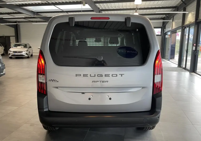 Vue arrière d’un Peugeot Rifter gris Artense avec feux verticaux LED et pare-chocs noir mat en showroom.