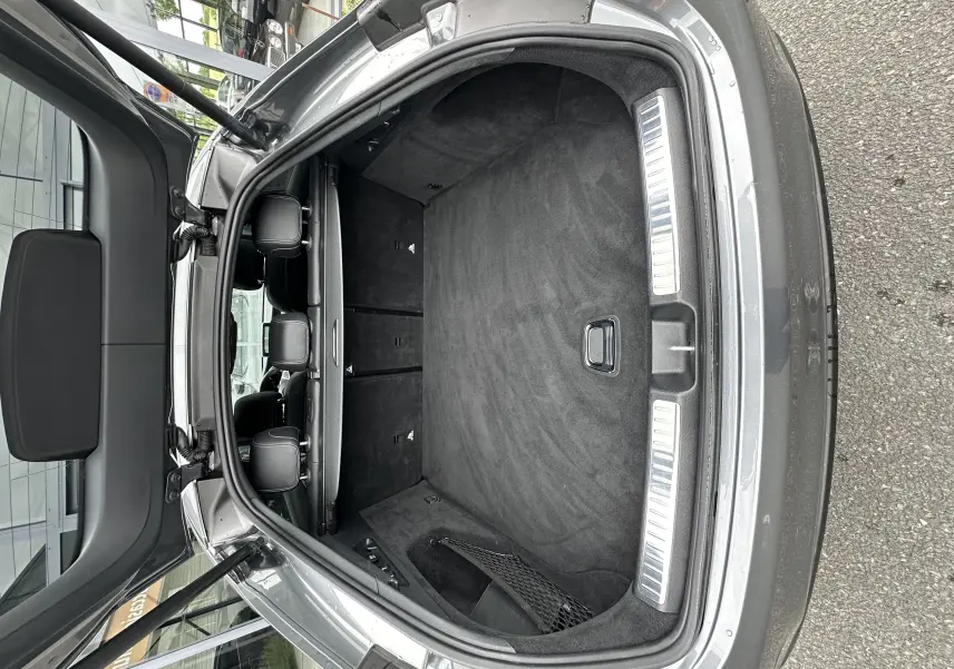 Coffre ouvert vu de l'arrière d'un Mercedes GLC Coupé 250 D Fascination gris foncé, intérieur noir et tapis propre.