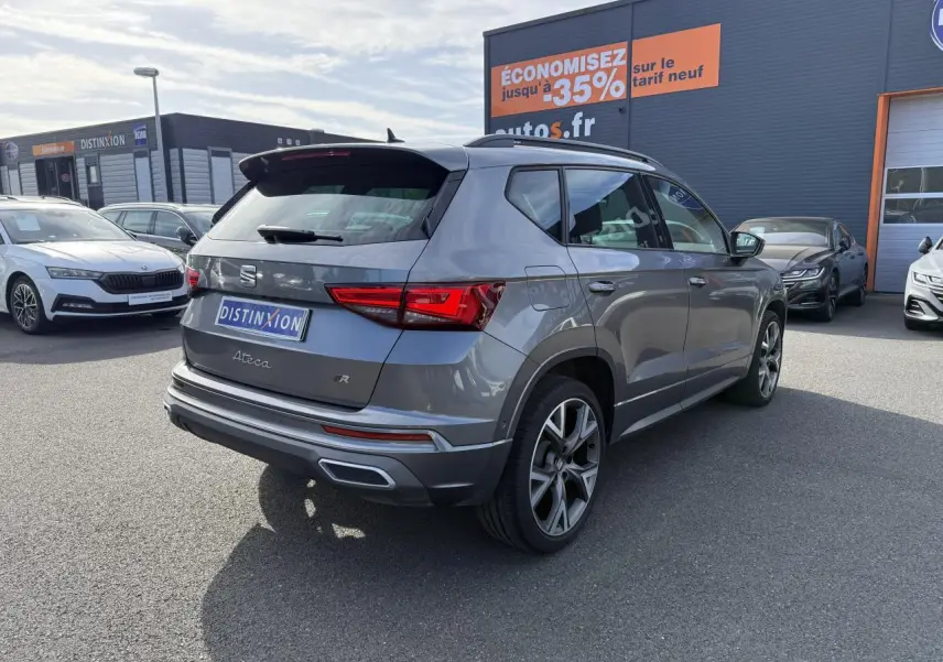 Vue 3/4 arrière droite d'un SEAT Ateca FR gris graphite avec jantes alu 19 pouces et feux LED arrière allumés.
