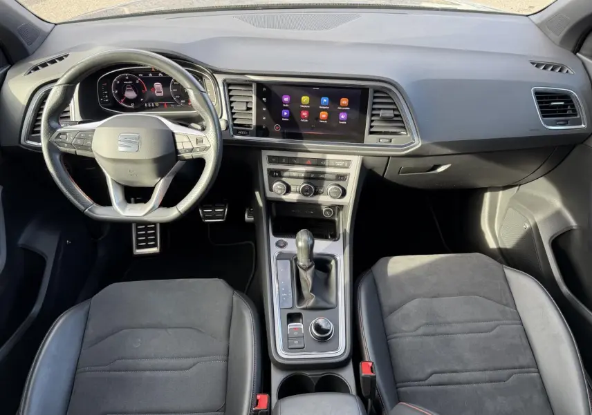 Vue intérieure frontale du tableau de bord et console centrale du SEAT Ateca gris graphite avec volant sport multifonction et écran tactile.
