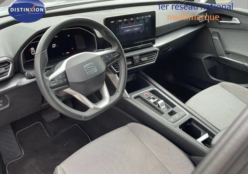 Vue intérieure côté conducteur du SEAT LEON ST 2023 gris urbain, tableau de bord moderne avec écran tactile central.