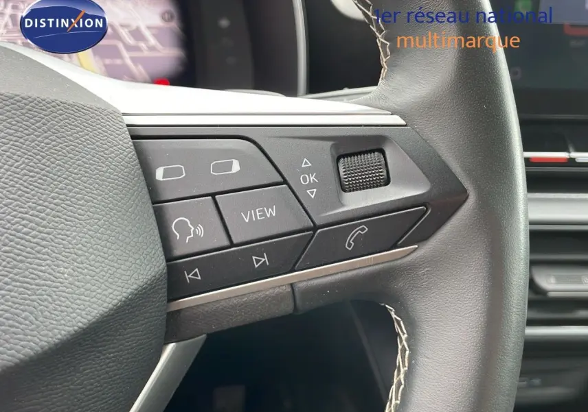 Gros plan sur les commandes multifonctions du volant en cuir noir du SEAT LEON ST gris urbain 2023.