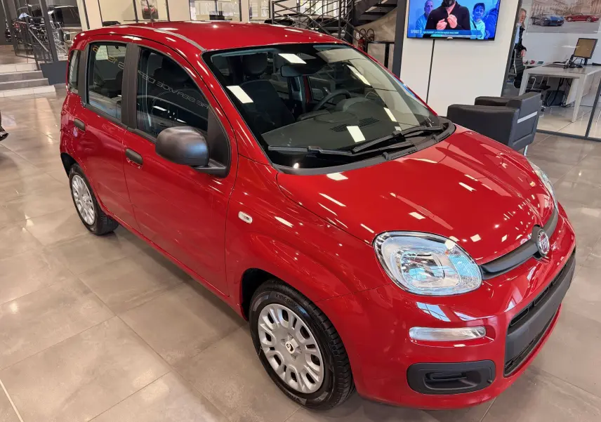 Vue 3/4 avant droite de la Fiat Panda 1.0 Hybrid 2025 en Rouge Amore, avec rétroviseurs noirs et jantes acier.