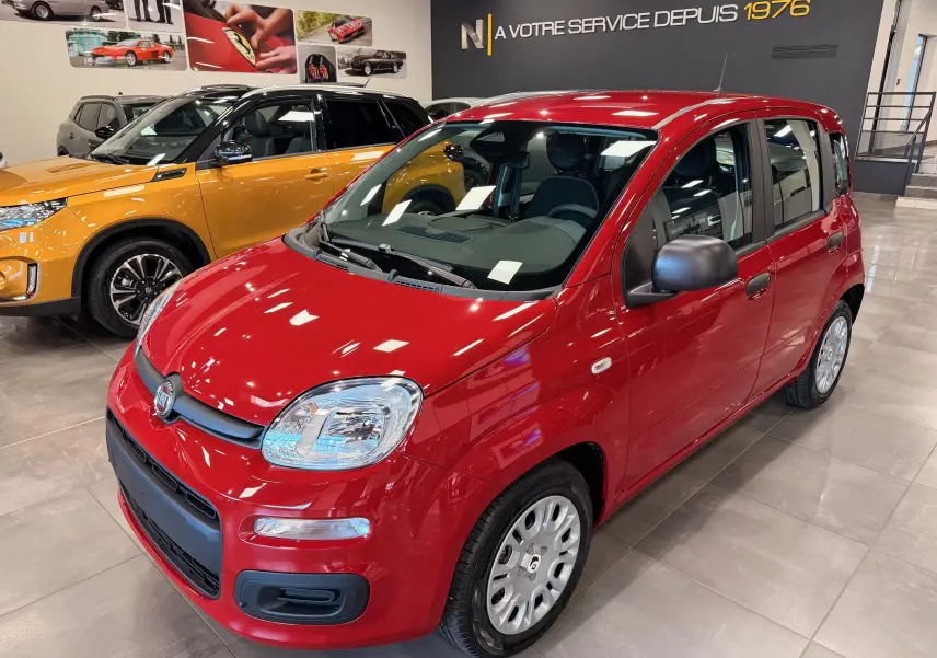 Vue 3/4 avant droite de la FIAT Panda 1.0 70 CH Hybrid City rouge Amore avec rétroviseurs noirs en concession.
