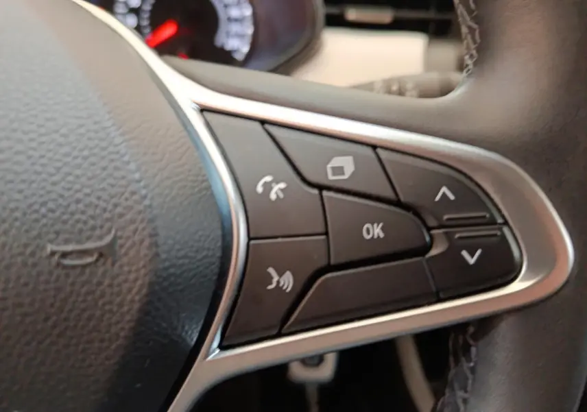 Gros plan sur les commandes multifonctions à droite du volant cuir synthétique de la Renault Clio blanche Evolution TCe 100 GPL 2023.