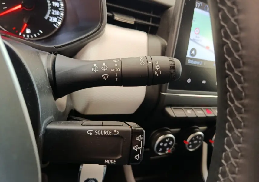 Gros plan sur la commande des essuie-glaces et le volant cuir synthétique de la Renault Clio Evolution TCe 100 GPL 2023.
