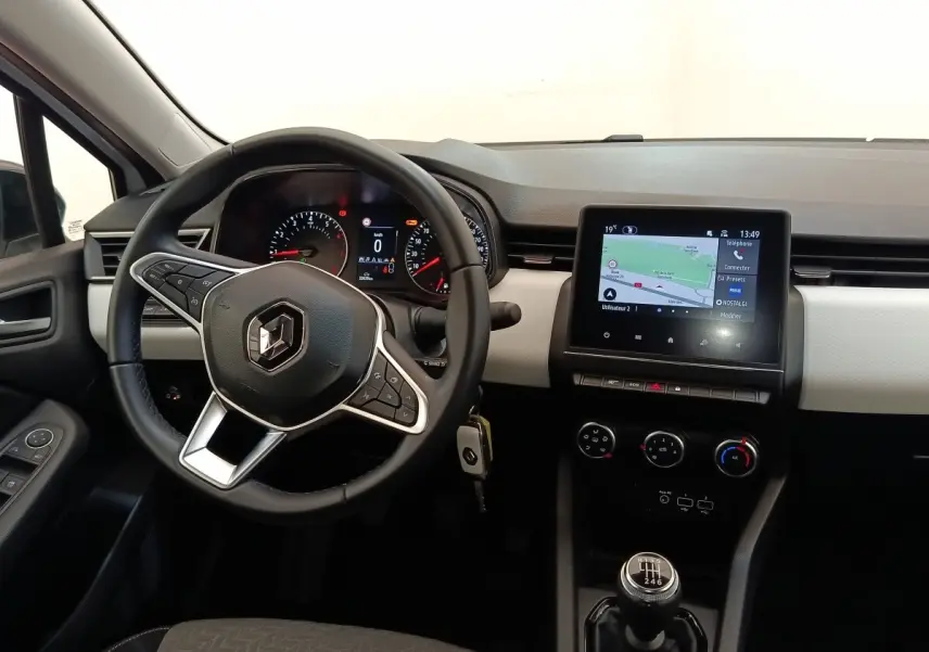 Vue intérieure avant de la Renault Clio blanche 2023, volant cuir multifonctions et écran tactile de navigation visible.