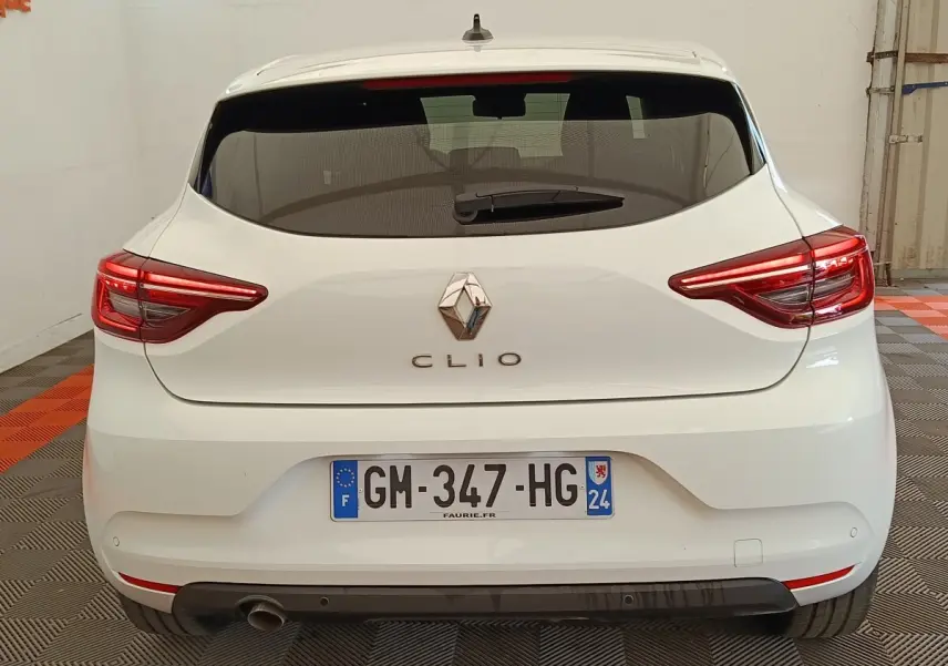 Vue arrière d'une Renault Clio blanche 2023 avec feux LED allumés et plaque d'immatriculation française visible.