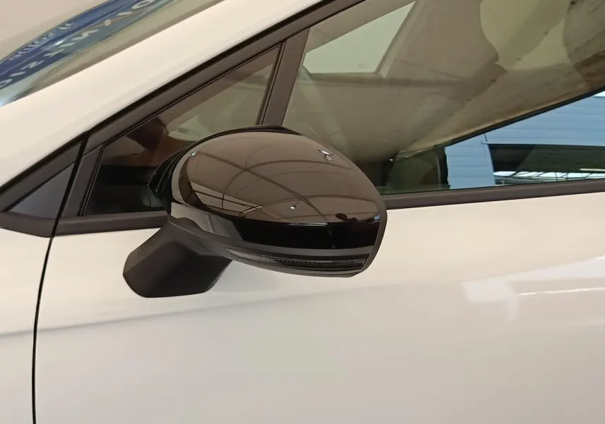 Gros plan sur le rétroviseur noir brillant côté conducteur d'une Renault Clio blanche Evolution TCe 100 GPL 2023.