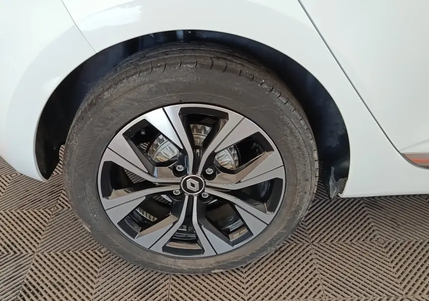 Gros plan sur la roue arrière droite de la Renault Clio blanche, avec jante alliage bicolore au design moderne.