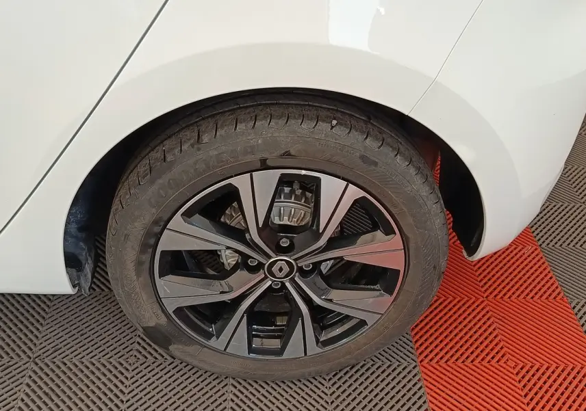 Gros plan sur la roue arrière droite d'une Renault Clio blanche avec jante alliage noire et argentée.