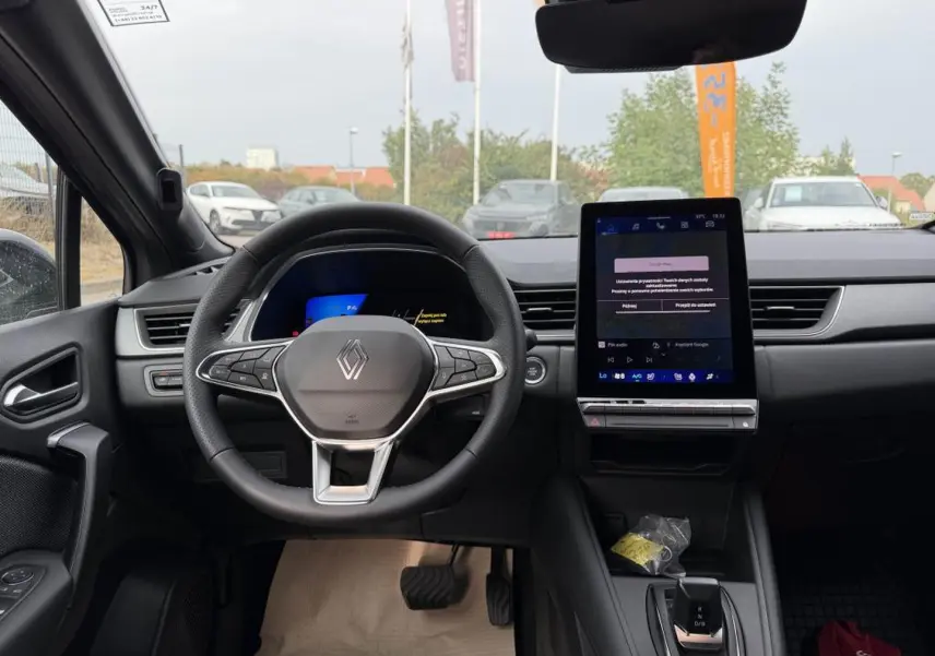 Vue intérieure frontale du tableau de bord gris cassiopé du Renault Symbioz avec volant multifonction et écran tactile vertical.