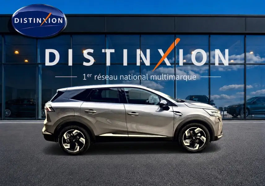 Profil côté gauche du Renault Symbioz gris cassiopée 2026 devant une vitrine avec logo Distinxion.