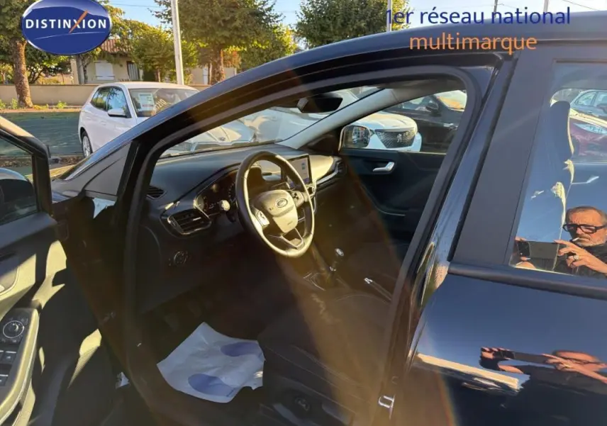 Vue intérieure côté conducteur d'un Ford Puma noir 2023 avec volant, écran tactile et sièges sport visibles.