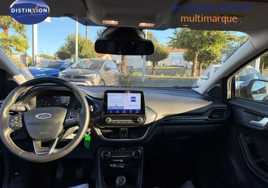 Vue intérieure avant du Ford Puma noir 2023, tableau de bord avec écran tactile et volant multifonction.