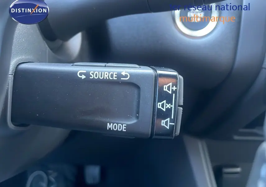 Gros plan sur la commande au volant du Renault Captur E-Tech hybride 2025 en noir étoile métal, avec boutons source et mode visibles.